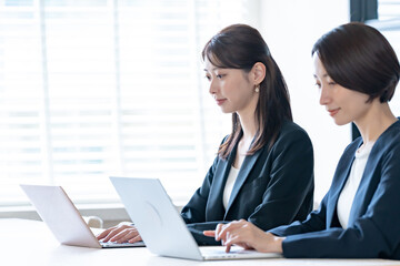Fototapeta premium パソコン仕事をする女性2人