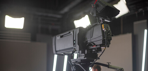 a television camera with a large zoom lens in a studio