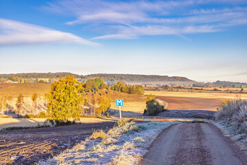 Rural landscape view at autumn with a gravel road and frost on the ground