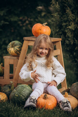 Fototapeta premium Little girl child in the garden with pumpkins