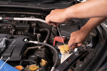 Asian man uses cable ties as temporary replacement nuts for basic car maintenance.