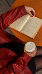 Fototapeta premium Woman reading a book and holding a coffee cup