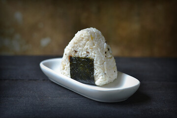 Onigiri rice balls on a black plate on a black wooden board. A typical Japanese dish