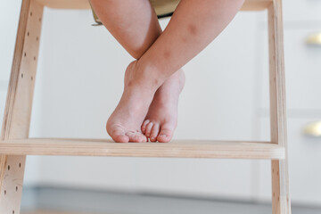 Cute bare feet of a child on the step of a high chair in the kitchen
