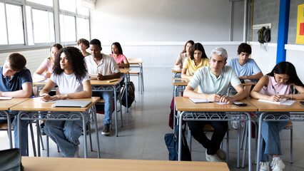 Multiethnic students taking exam in classroom at high school