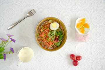 Close-up of rice noodles on a white lace background, eggs, carrots, top view