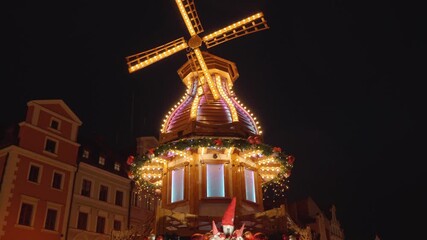 Christmas fair at night with illuminated gifts and festive carousel in historic city center. Festive Christmas market in Wroclaw, Poland. Concept of holiday celebration, winter tradition and tourism