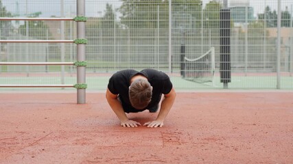 Young man doing push ups on a red outdoor court, engaging in intense calisthenics training and building strength for a healthy lifestyle, low static camera, slow motion - Powered by Adobe