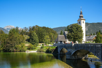 Church of St. John the Baptist and stone bridge in Ribčev Laz on Lake Bohinj (Bohinjsko jezero). It is the largest natural lake in Slovenia and is located in the Julian Alps, Triglav National Park