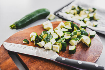 chopped zucchini on wooden board with knife on kitchen bench
