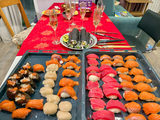 Homemade sushi made for guests at a party. In the background are glasses of champagne wine.