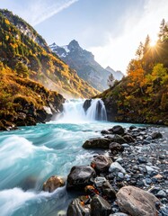 Beautiful landscape with vibrant turquoise river rushing towards waterfall in mountain range with autumn foliage under bright sky