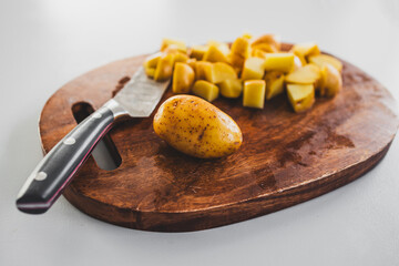 chopped baby potatoes on wooden board with knife on kitchen bench