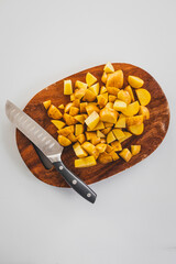 chopped baby potatoes on wooden board with knife on kitchen bench