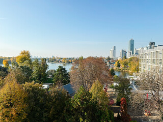 Autumn cityscape by the lake with modern skyline and colorful trees in Vienna, Austria.