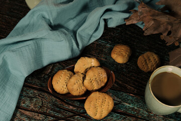 hot drink in blue mug with homemade cookies, dry leaves decoration, fall autumn vibes, rustic cozy seasonal mood