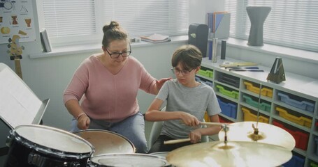 Talented Boy Playing Drums During Percussion Class in Elementary School, Developing Sense of Rhythm. Teacher Teaching Young Musician to Play Drum Kit on Music Lesson. Musical Instruments Learning.