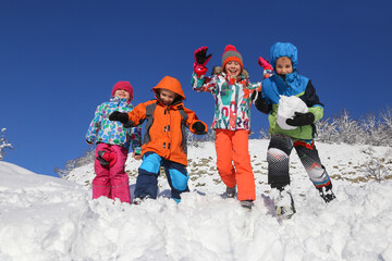 Group of children playing on snow in winter time