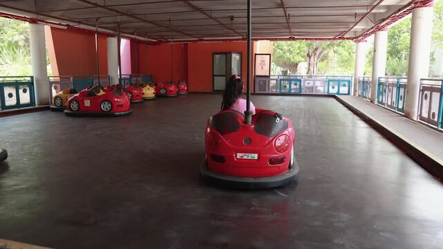 Kids enjoying bumper car rides at amusement park during sunny afternoon