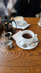 Close-up of hot drip coffee with cream sugar pearl pancake and caramel crème brûlée on a wooden table in a stylish elegant Daikanyama Ginza Tokyo café, cozy autumn winter afternoon tea set atmosphere
