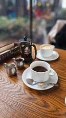 Close-up of hot drip coffee with cream sugar pearl pancake and caramel crème brûlée on a wooden table in a stylish elegant Daikanyama Ginza Tokyo café, cozy autumn winter afternoon tea set atmosphere