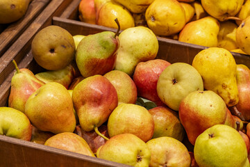 A close-up of fresh yellow pears and green oranges displayed at a market, showcasing their natural texture and vibrant colors.