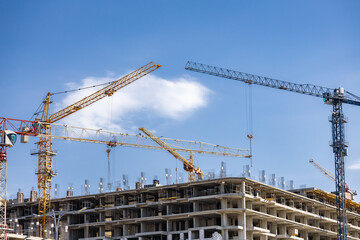 A crane in front of a building under construction. The sky is clear and blue. construction of a multi-storey building