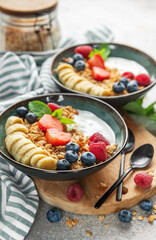 Healthy breakfast bowls with yogurt, granola, banana, and berries
