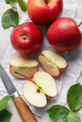 Freshly cut red apples on baking paper with knife and leaves