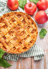 Freshly baked apple pie with red apples and leaves on rustic wooden table