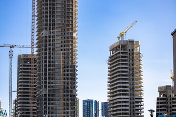 Fototapeta premium Construction crane on Housing. Construction site with buildings under construction. Tower cranes in action. Crane during formworks. Multi Storey Residential Buildings construction.