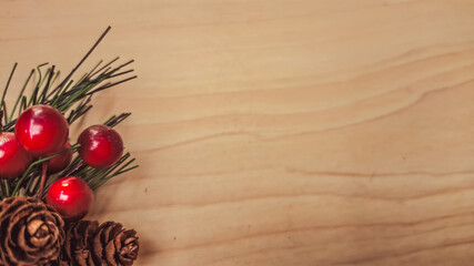 Holiday evergreen pinecone and red berries branch on textured wooden surface. Perfect concept for Christmas decoration, seasonal background, festive inspiration, and natural winter arrangement.