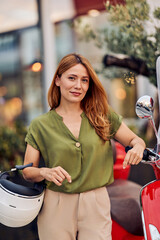 Confident Woman Standing Beside a Stylish Red Scooter Holding a Helmet
