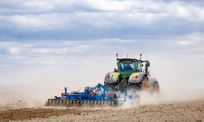 Fototapeta premium Farmer in tractor preparing land for sowing. Farmer in tractor preparing land with seedbed cultivator
