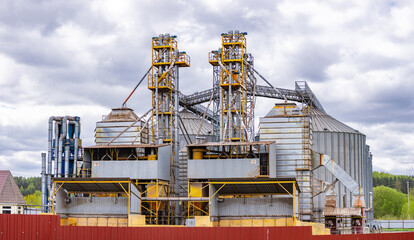 modern granary elevator with silver silos on agro-processing and manufacturing plant for processing drying cleaning and storage of agricultural products, flour, cereals and grain.