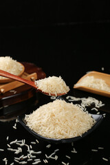 White Rice Grains in Wooden Spoons and Bowls on Black Background