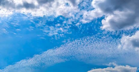 Shifting atmospheric fronts in the upper and lower atmosphere. A panorama of cirrus and cumulus clouds viewed from below. A dramatic meteorological celestial spectacle. Blue skies in turmoil.