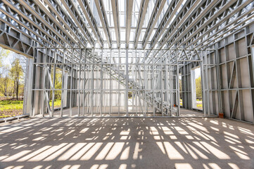 New technology steel frame for construction. Metal frame of the building with a sandwich panel of insulation on the wall. Construction of a new industrial building.