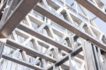 Obraz premium Structure of steel roof frame for building construction. Metal frame of the building with a sandwich panel of insulation on the wall. Construction of a new industrial building.