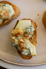 crispy crostini topped with fresh pear slices and creamy blue cheese. Perfect for illustrating elegant fall appetizers, holiday party snacks