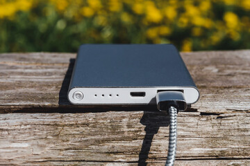 Close-up of a compact silver power bank with its cord plugged in.