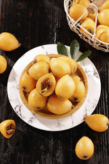 Fresh Loquat Fruits in Wooden Bowl with Basket on Rustic Table - Asian Tropical Fruit Display