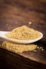 Ground Ginger Powder Spice in White Spoon on Wooden Table - Natural Cooking Seasoning Ingredient