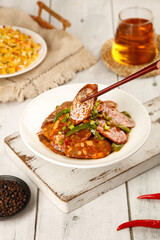 Spicy Sichuan Smoked Sausage Dish with Chopsticks on Rustic Wooden Board - Traditional Chinese Homemade Cuisine