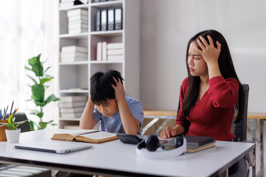 Stressed asian mother and son having difficulty with homework and finances at home
