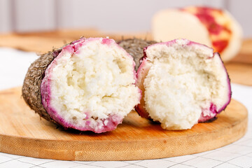 Fresh Purple Yam Sweet Potato Cut Open Showing White Heart Flesh on Wooden Board