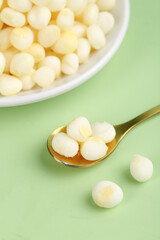 Fresh Peeled Corn Kernels in Bowl and Spoon on Green Background