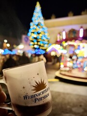  Christmas market scene in Potsdam, Germany. Large Christmas tree adorned with blue and gold lights...