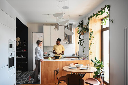 Couple talking in modern kitchen with plants and natural light