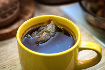 Yellow ceramic mug with oversteeped tea, showing a surface film and dark stains